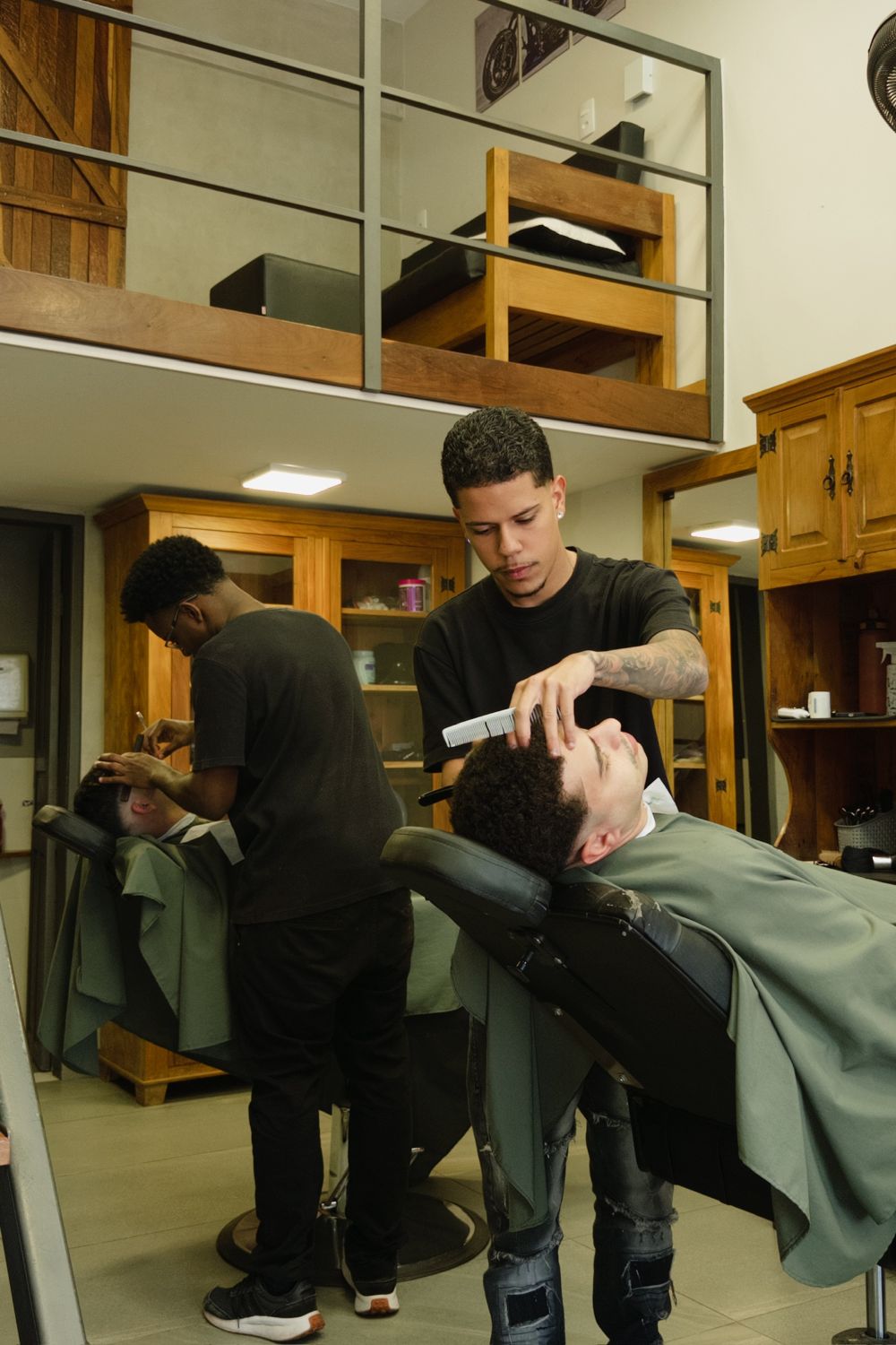 Dois barbeiros da Barbearia 08 atendendo clientes no salão