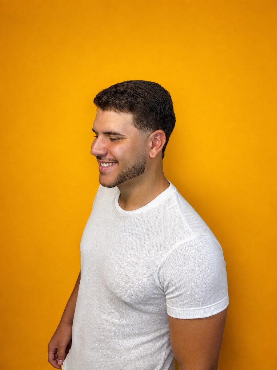 Cliente da Barbearia 08 com corte masculino finalizado, em fundo amarelo
