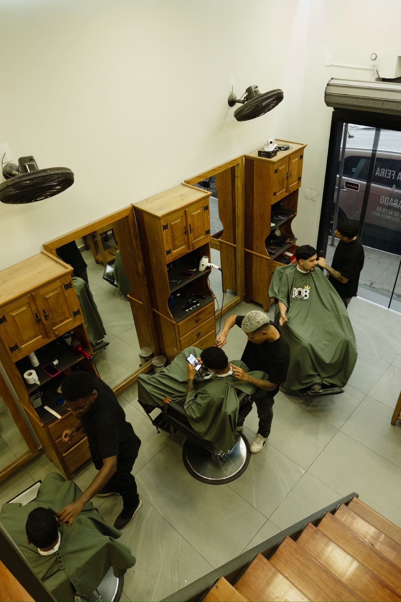 Vista superior do salão da Barbearia 08 com barbeiros atendendo clientes