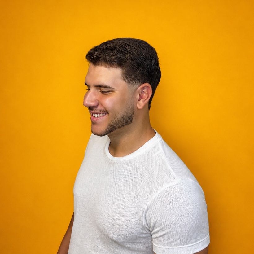 Cliente da Barbearia 08 sorrindo após o corte, em fundo amarelo